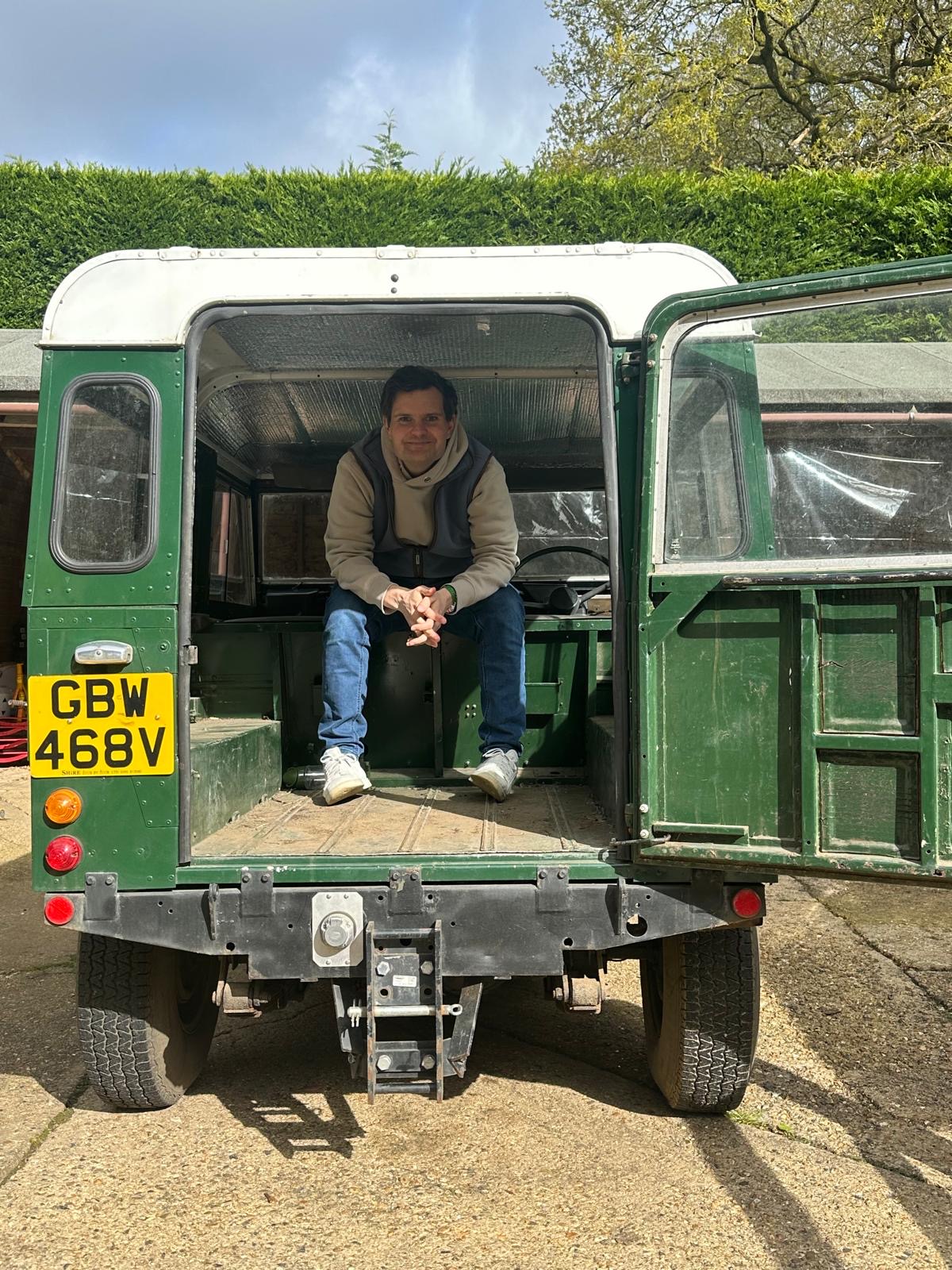Alex Davey, car buying agent UK, standing with a classic Land Rover Defender