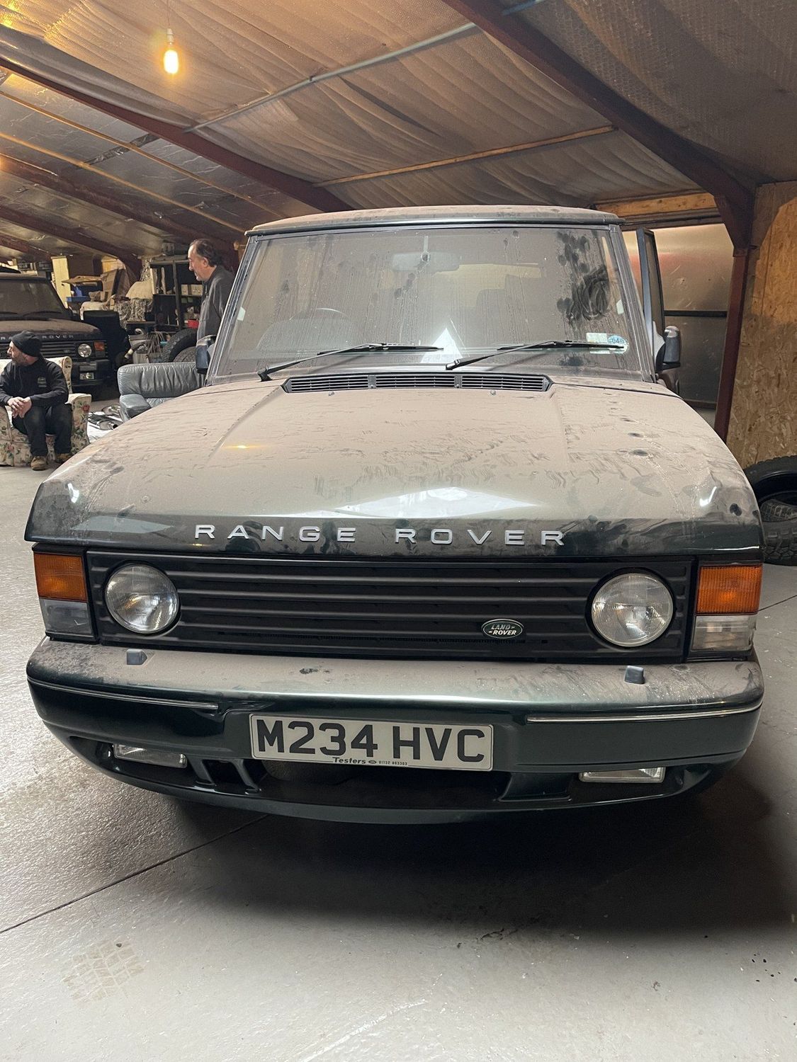 A dusty green Range Rover Classic in a barn