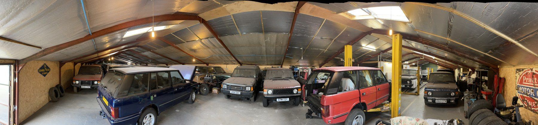 Several classic cars kept together under cover in a barn